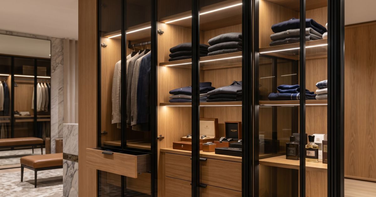 Ekskluzywna garderoba na wymiar z podświetlanymi półkami LED, szklanymi drzwiami i eleganckim drewnianym wykończeniem.